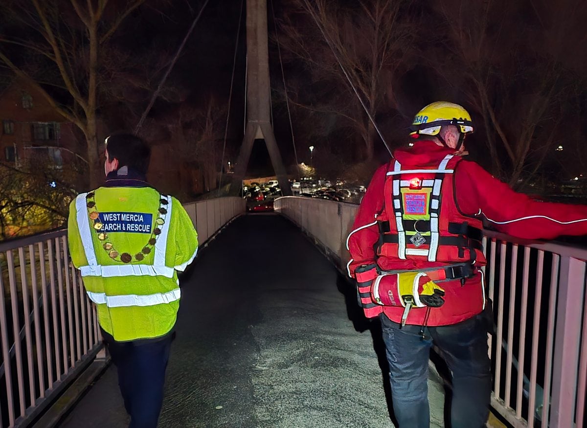 Two West Mercia Search and Rescue volunteers on a footbridge during a night river patrol